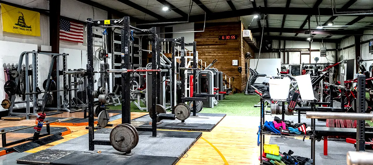 The platform end of the floor, with bumper plates stacked and a barbell loaded on the wood.